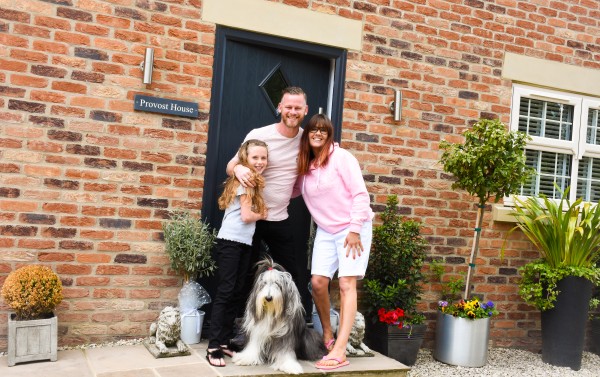 James in front of his self-build home with his family